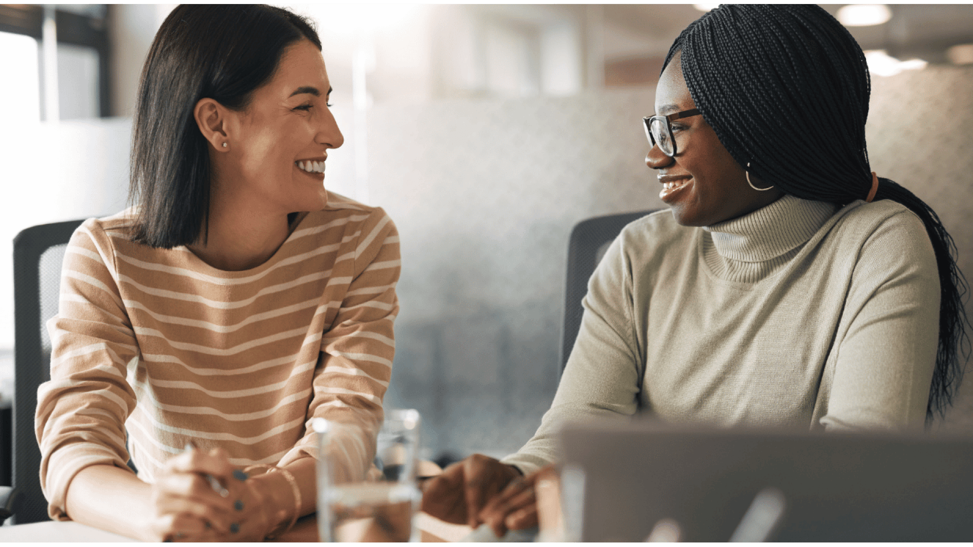 Two women sat side by side smiling at each other