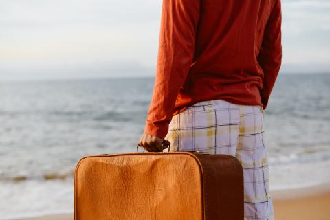 A photo of a person holding a suitcase by the sea